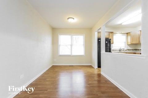 an empty living room and kitchen with wood flooring and a window