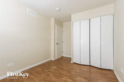 a bedroom with two white closets and a wooden floor