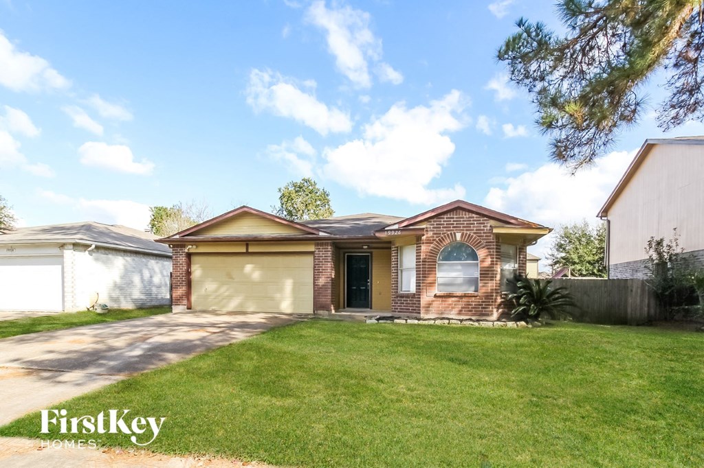 the front of a brick house with a lawn and a garage