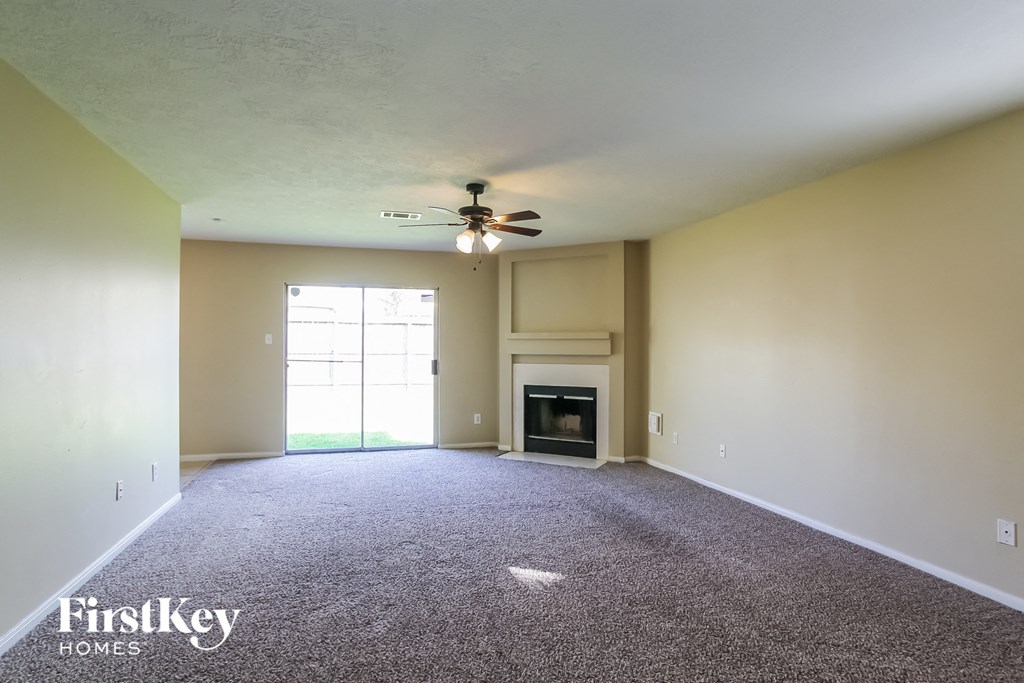 an empty living room with a ceiling fan and a fireplace
