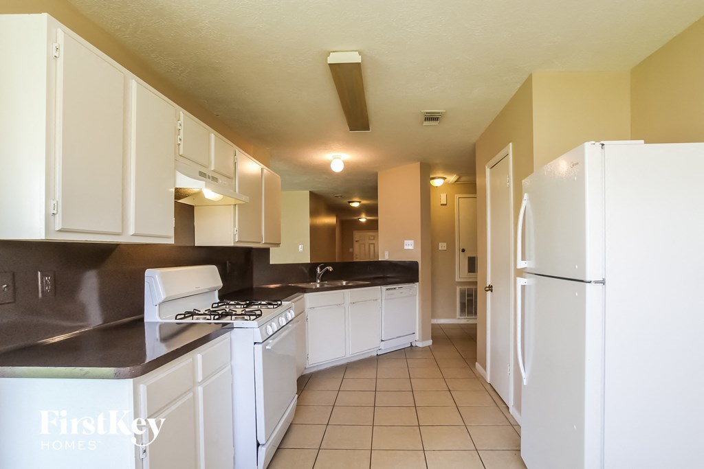a kitchen with white appliances and white cabinets and a refrigerator