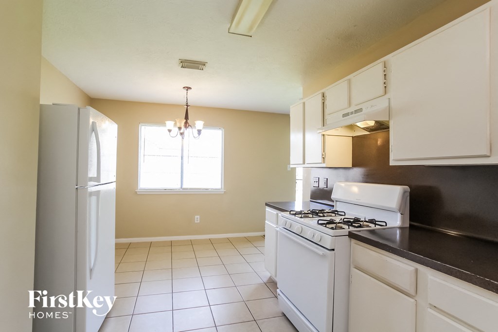 an empty kitchen with white appliances and a refrigerator
