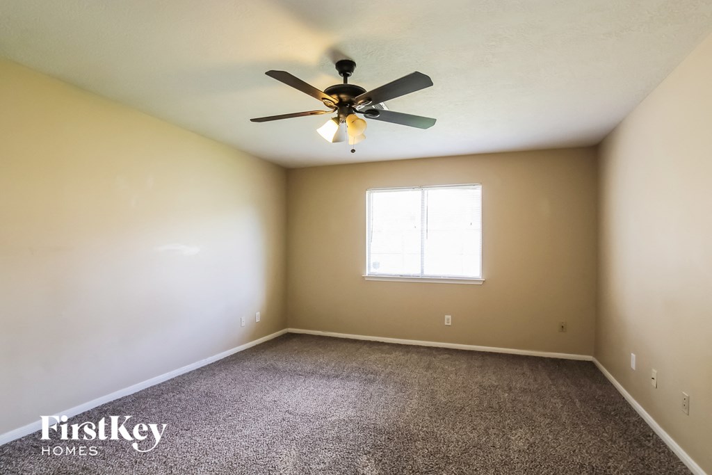 an empty room with a ceiling fan and a window