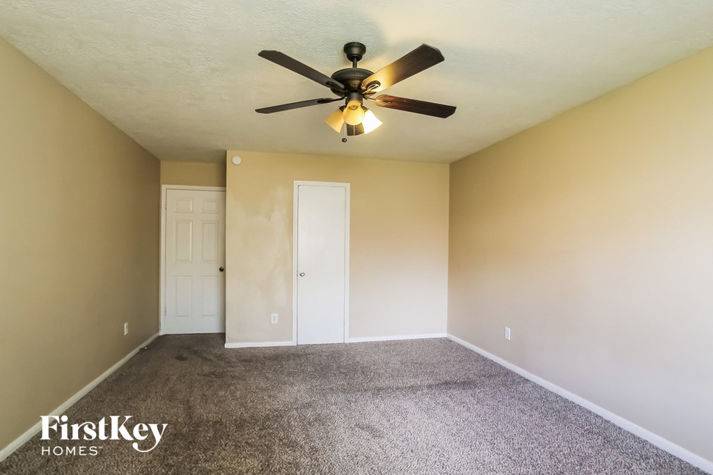 an empty room with a ceiling fan and a door