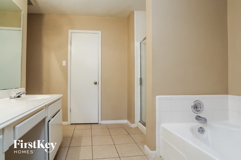 a bathroom with a tub and a shower and a sink