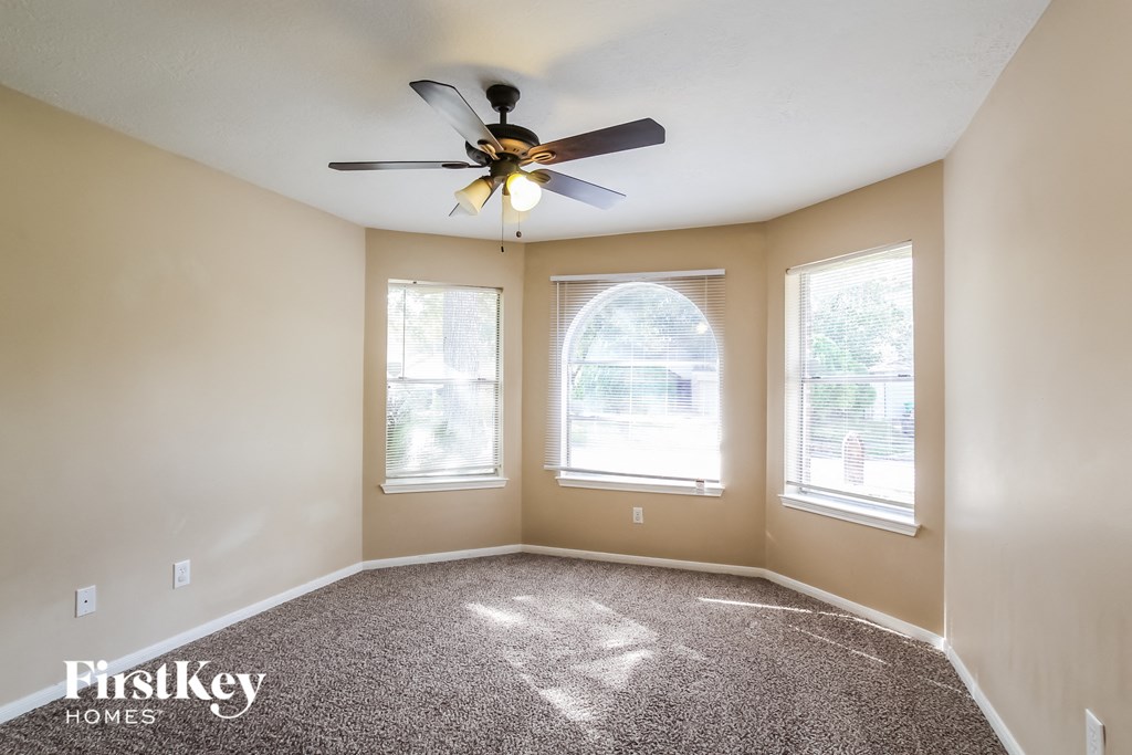an empty room with a ceiling fan and two windows