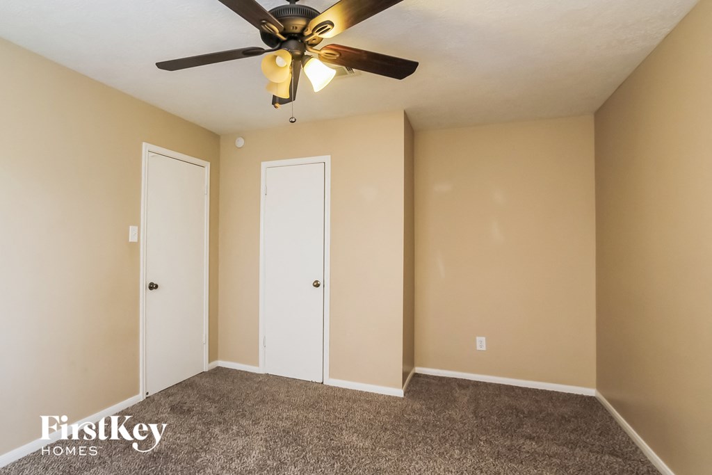 a empty room with a ceiling fan and two doors