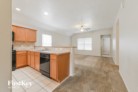 a kitchen with wood cabinets and black appliances and a carpeted floor