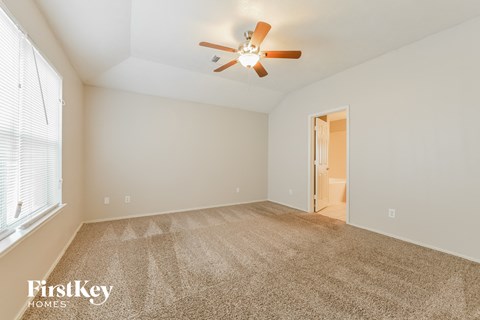 a spacious living room with carpet and a ceiling fan