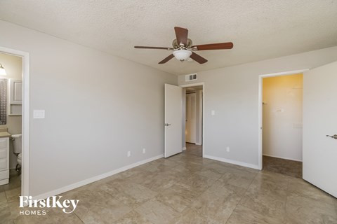 a living room with a ceiling fan and a door to a bathroom