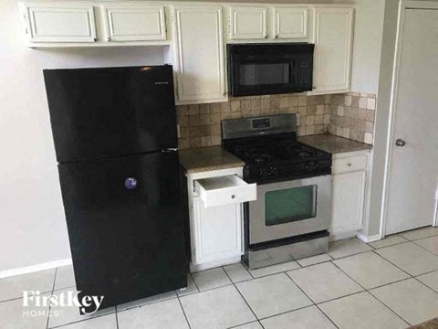 a kitchen with a black refrigerator and a stove