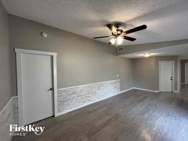 A room with a ceiling fan and wooden flooring.