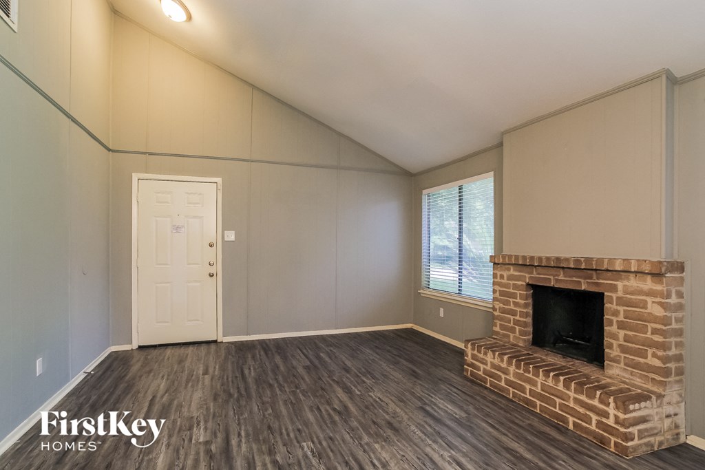 the living room of an empty house with a brick fireplace