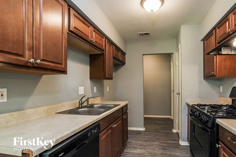 a kitchen with a sink and a stove and wooden cabinets