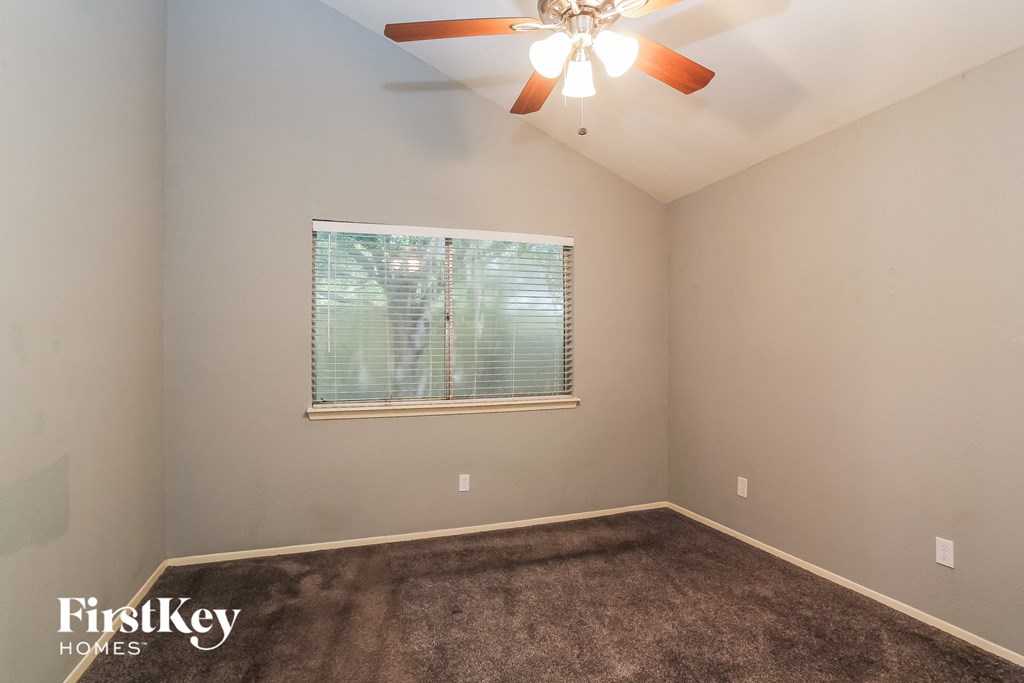 the living room of an empty house with a window and a ceiling fan