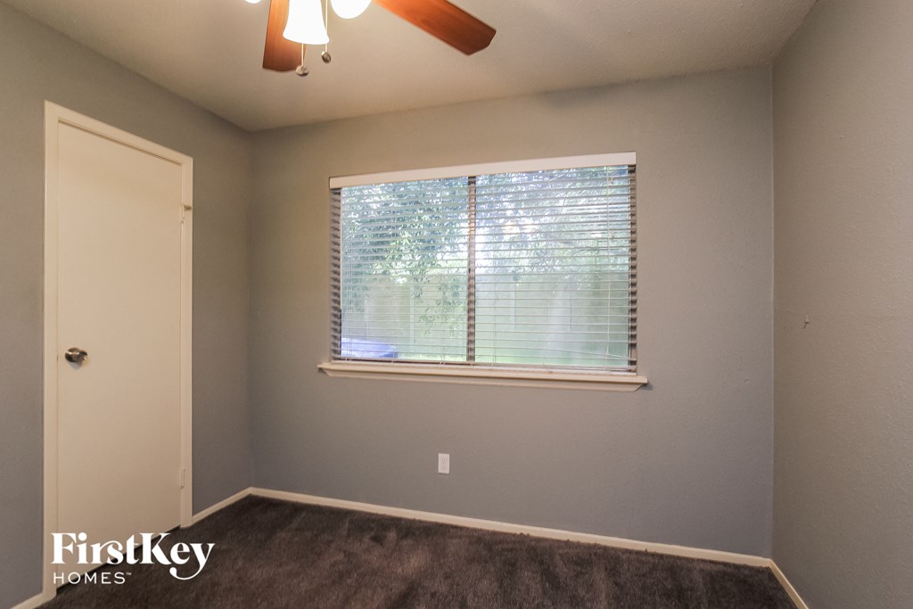 a bedroom with a large window and a ceiling fan