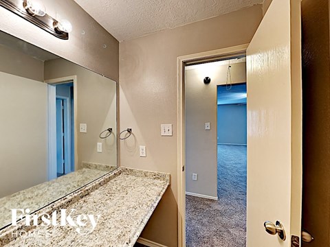 A bedroom with a mirror and a door leading to a hallway.