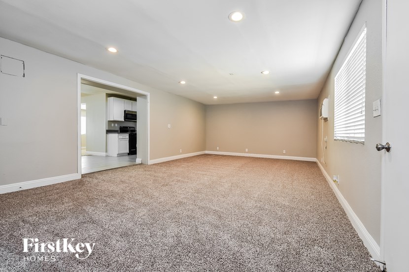 A spacious room with a carpeted floor and a doorway leading to another room.