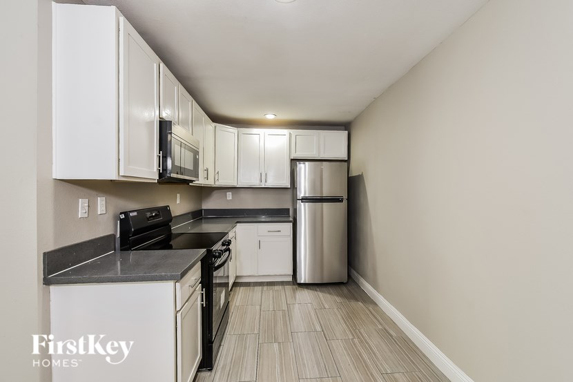 A kitchen with white cabinets and a black countertop.