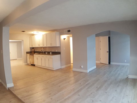 A kitchen with white cabinets and a wooden floor.