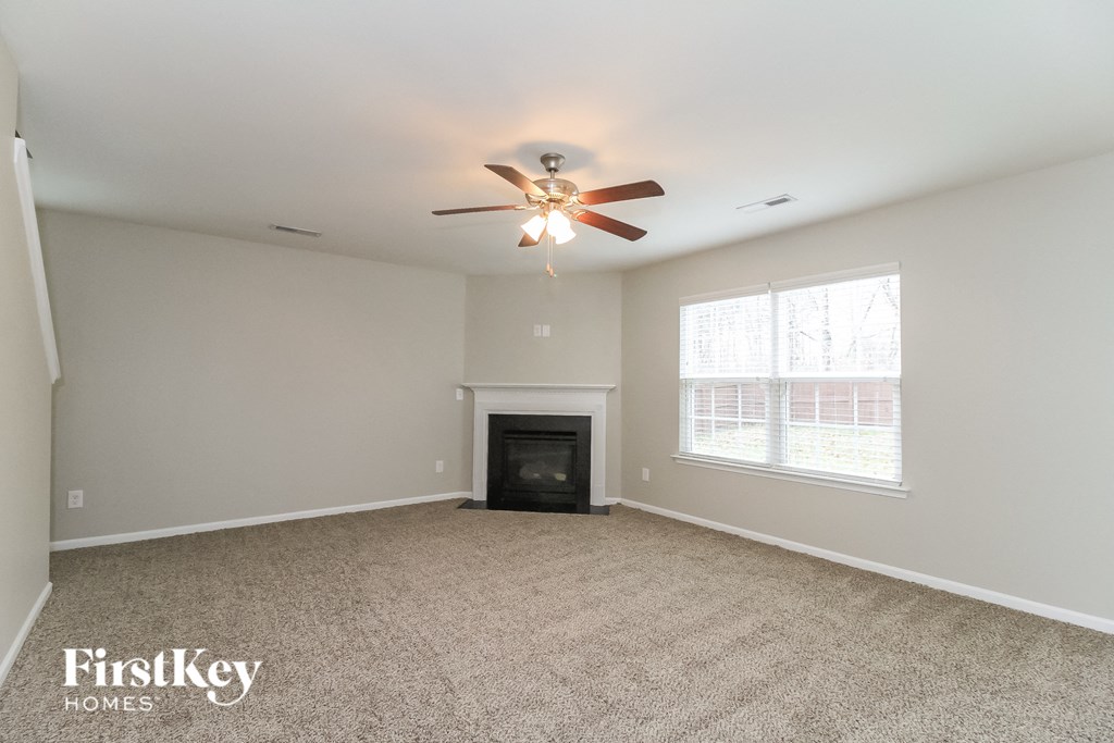 A spacious room with a fireplace and a ceiling fan.