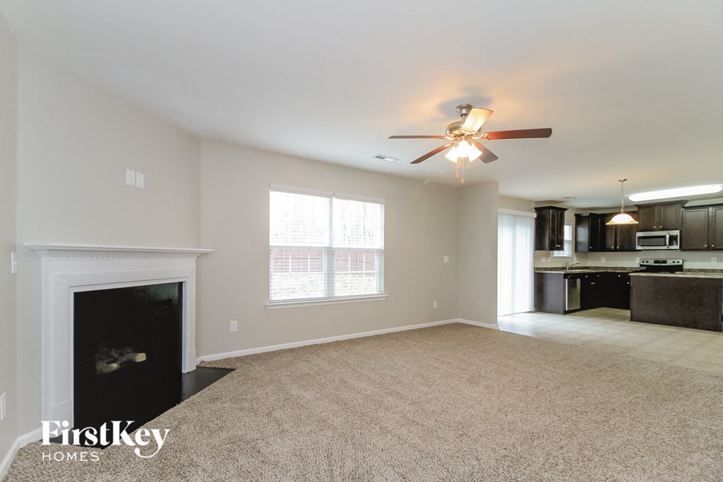A spacious living room with a fireplace and a ceiling fan.
