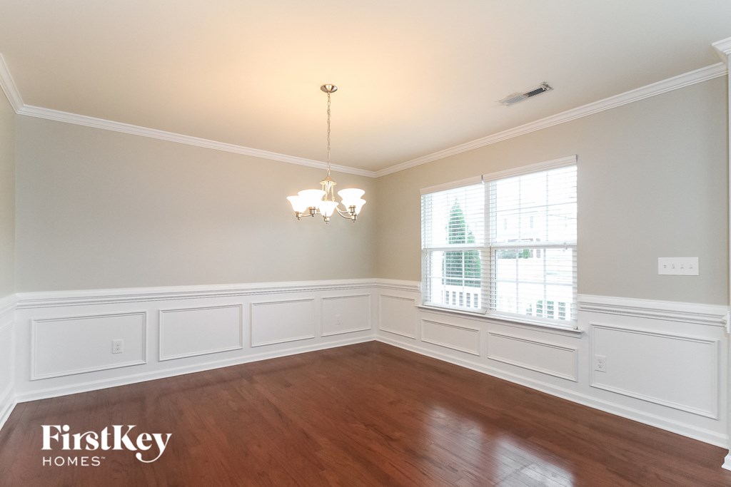 A room with wooden floors and a chandelier hanging from the ceiling.