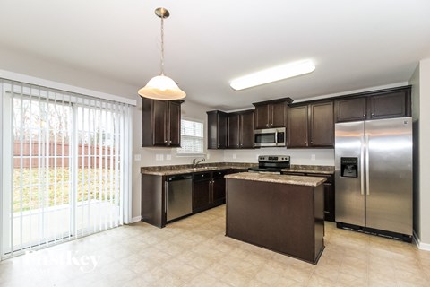 A kitchen with a refrigerator, microwave, and oven.