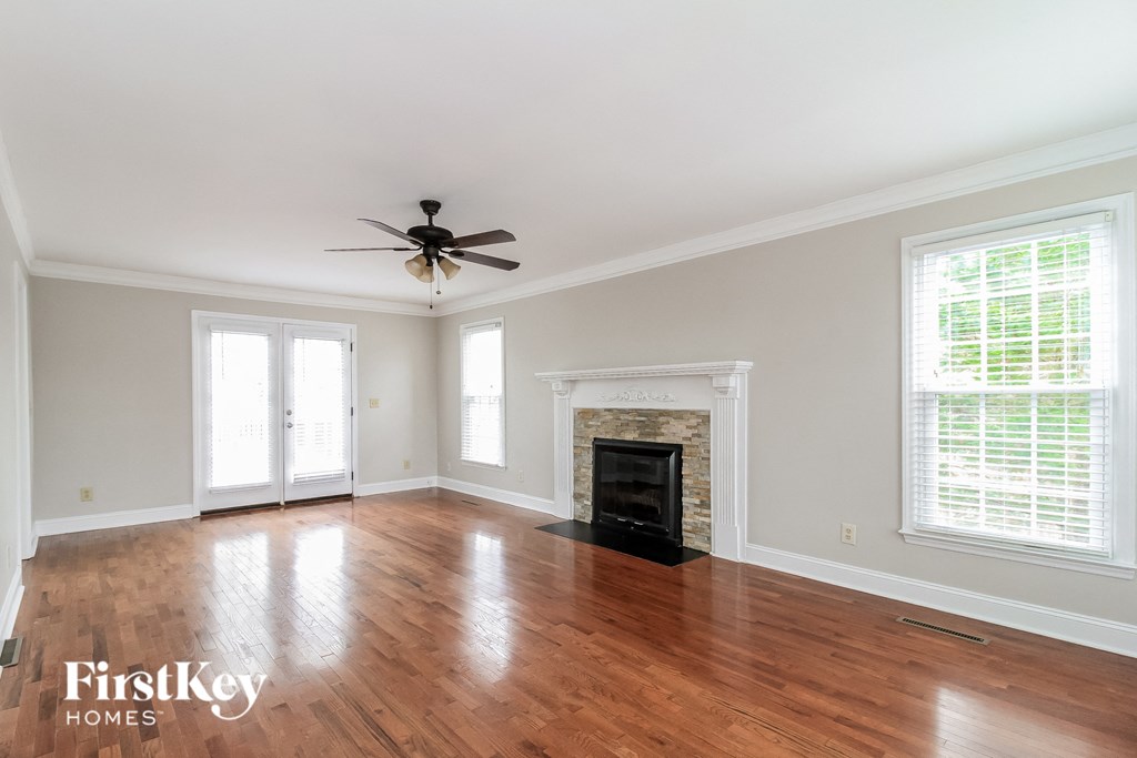an empty living room with a fireplace and a ceiling fan