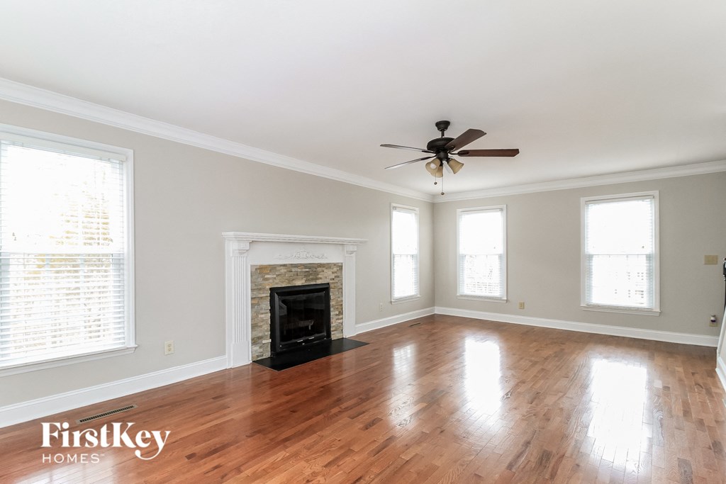 an empty living room with a fireplace and a ceiling fan