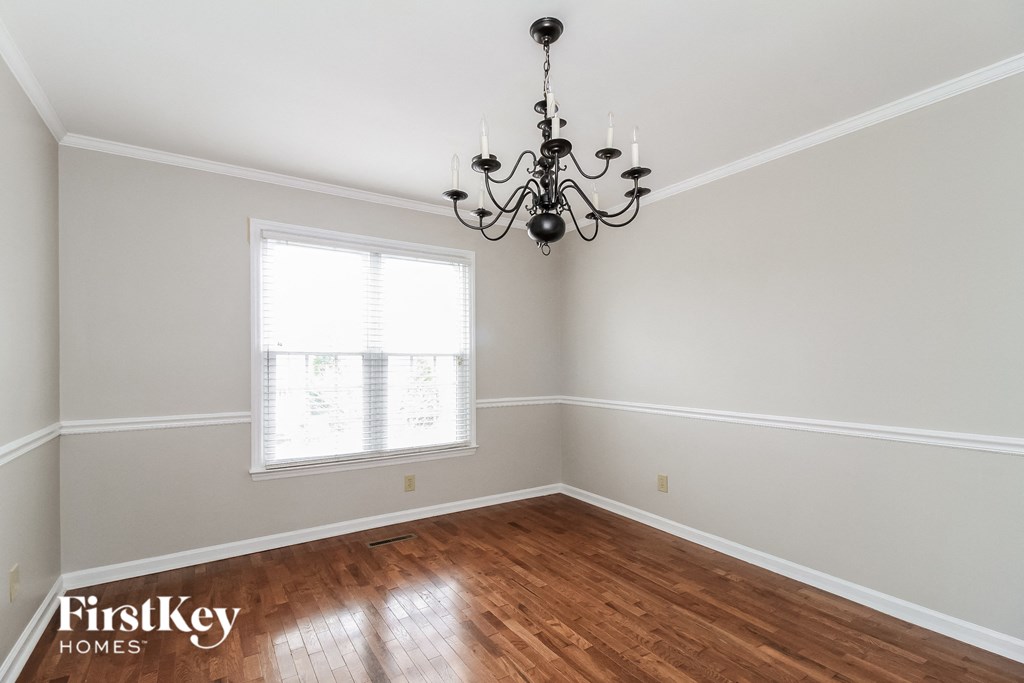 an empty dining room with a chandelier and a window