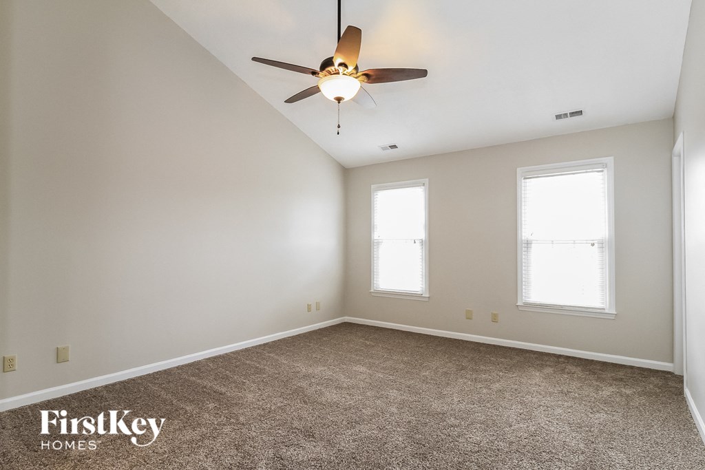 an empty room with a ceiling fan and two windows