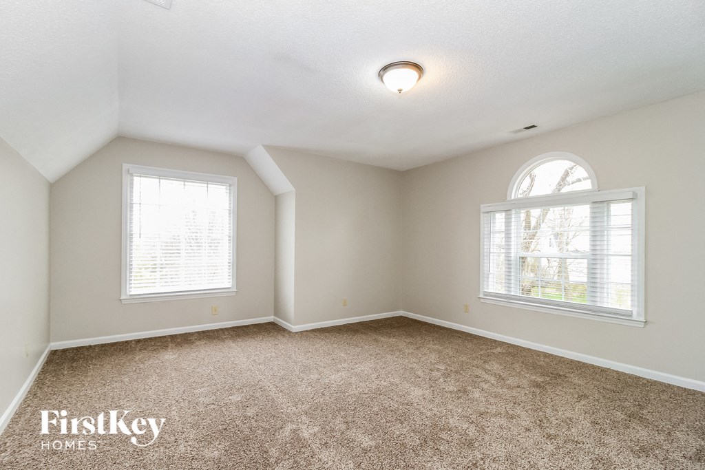 an empty living room with carpet and two windows