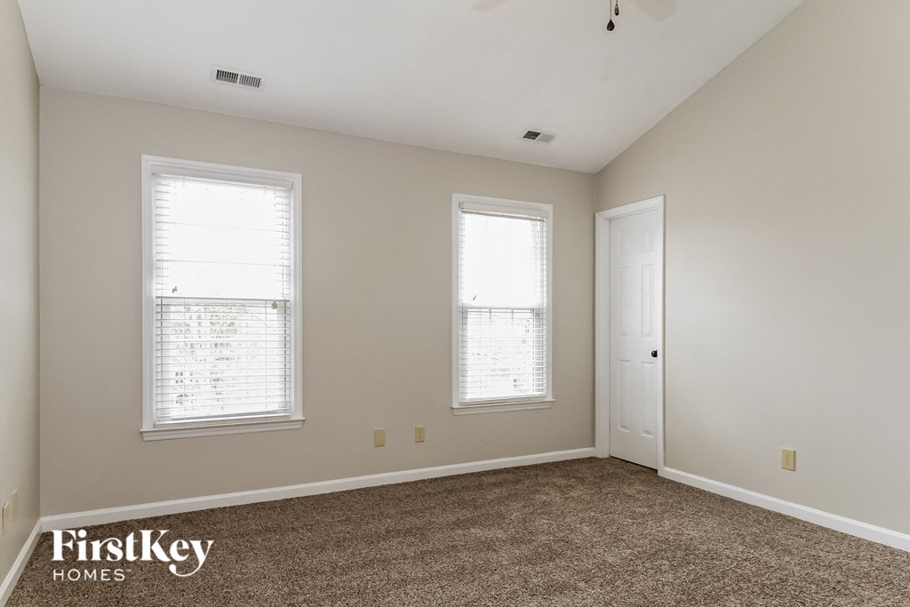 a bedroom with a carpeted floor and two windows