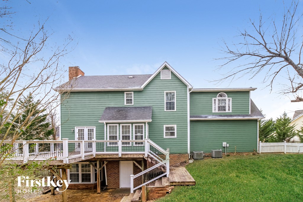 a green house with a deck and a white fence