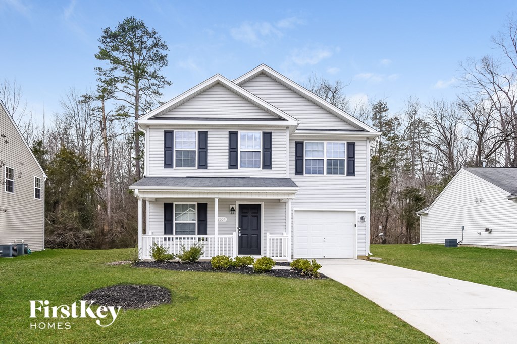 a white house with black shutters and a sidewalk in front