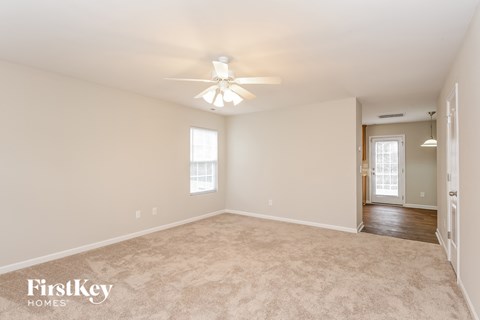 a spacious living room with carpet and a ceiling fan