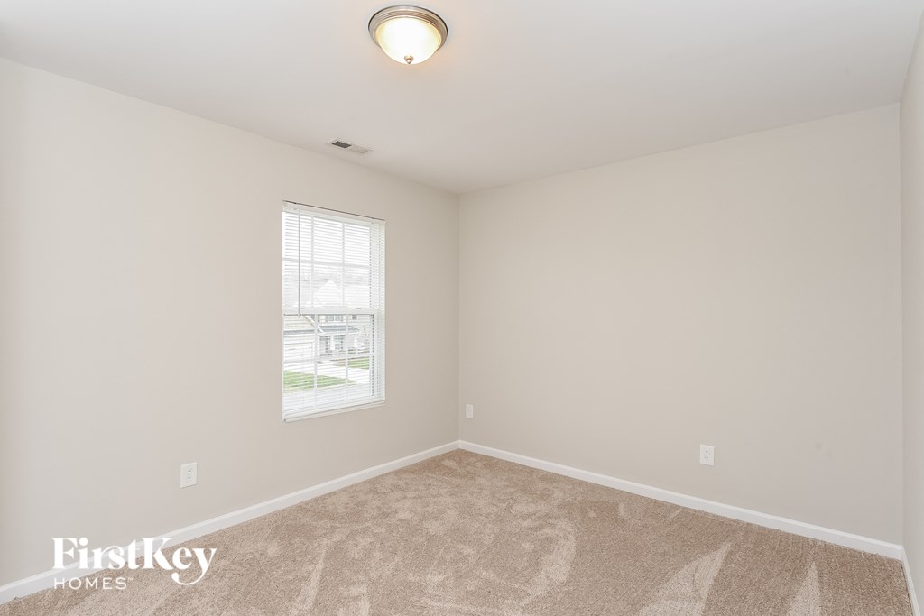 a bedroom with white walls and carpet and a window
