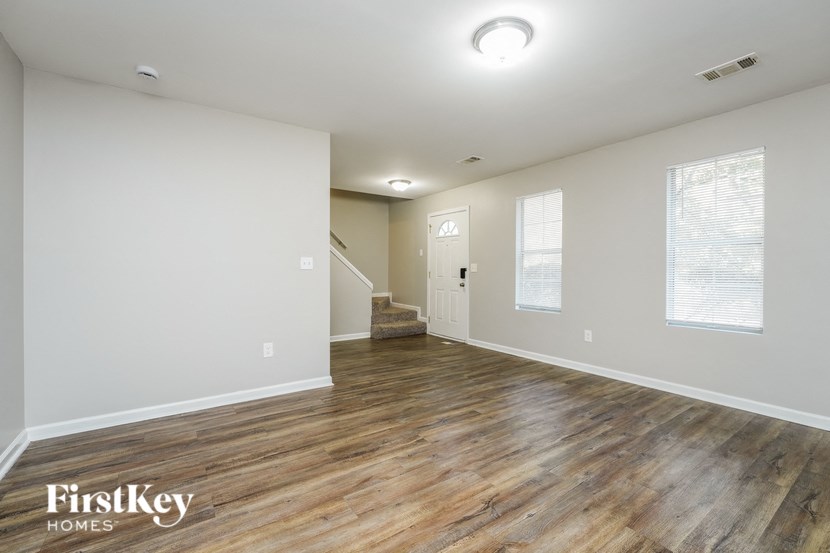 an empty living room with wood flooring and white walls