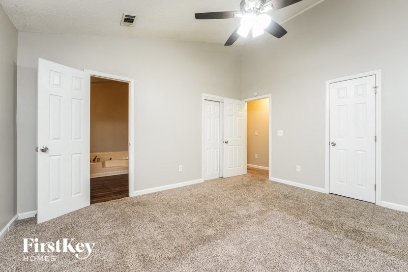 an empty living room with white doors and a ceiling fan