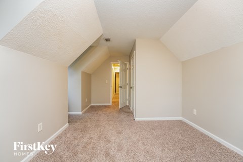 a spacious living room with carpet and a hallway to a bedroom