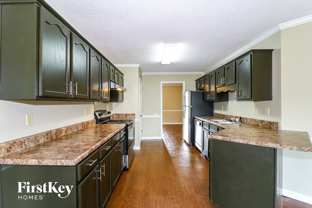 A kitchen with dark green cabinets and a granite counter top.