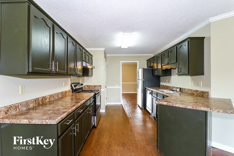 A kitchen with dark green cabinets and a granite counter top.