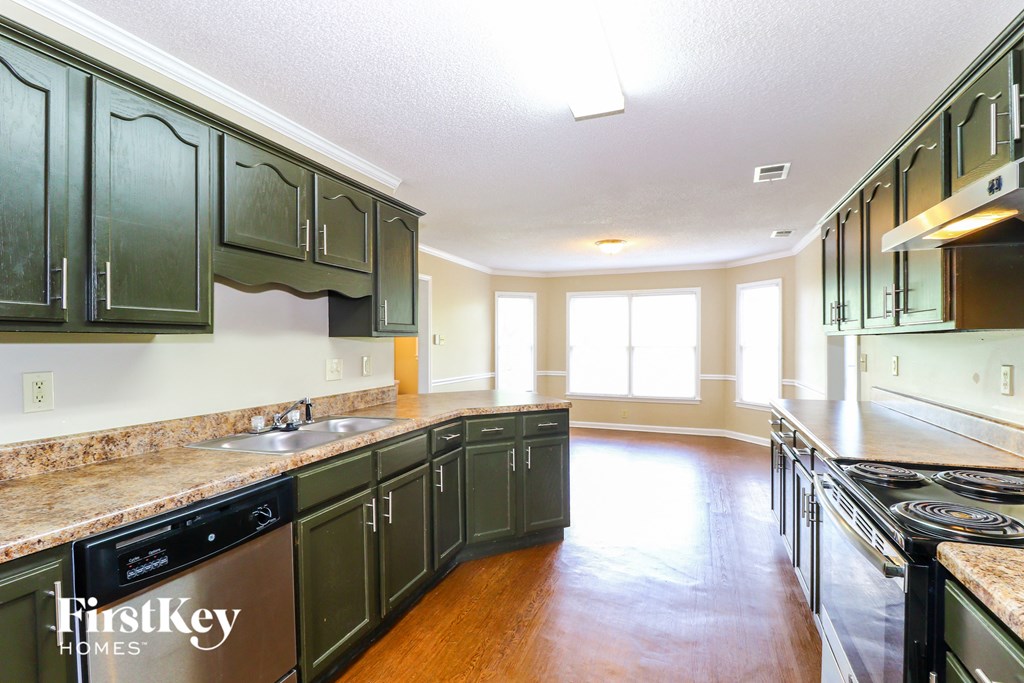 A kitchen with dark green cabinets and a stainless steel dishwasher.