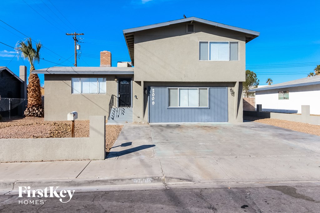 an empty driveway in front of a house with a blue sky