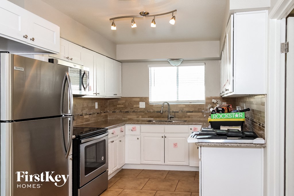 a white kitchen with stainless steel appliances and white cabinets