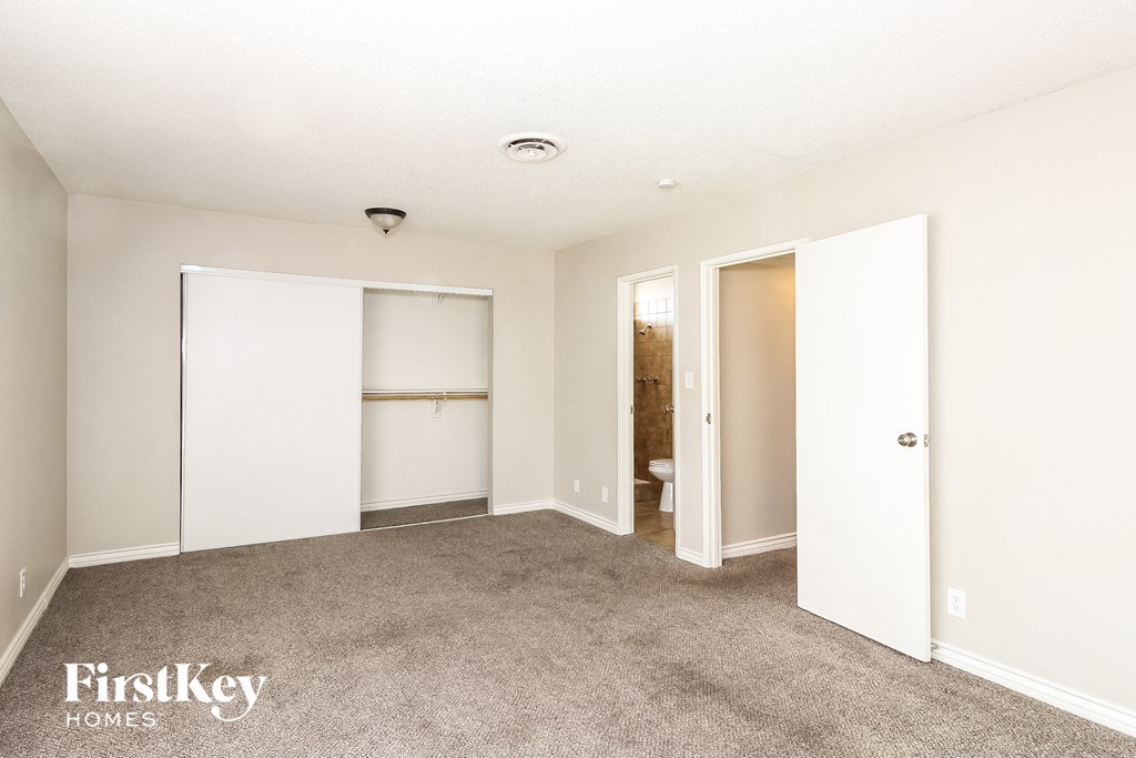 a bedroom with white walls and carpet and white closets