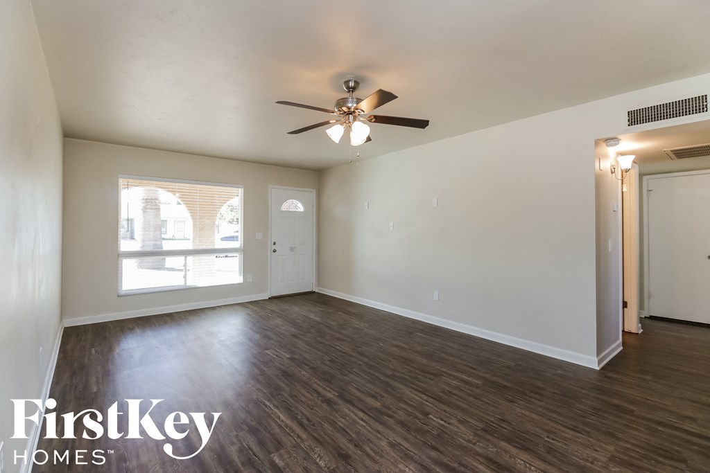 an empty living room with wood flooring and a ceiling fan