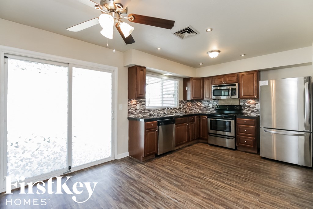 a kitchen with wood flooring and stainless steel appliances and a ceiling fan