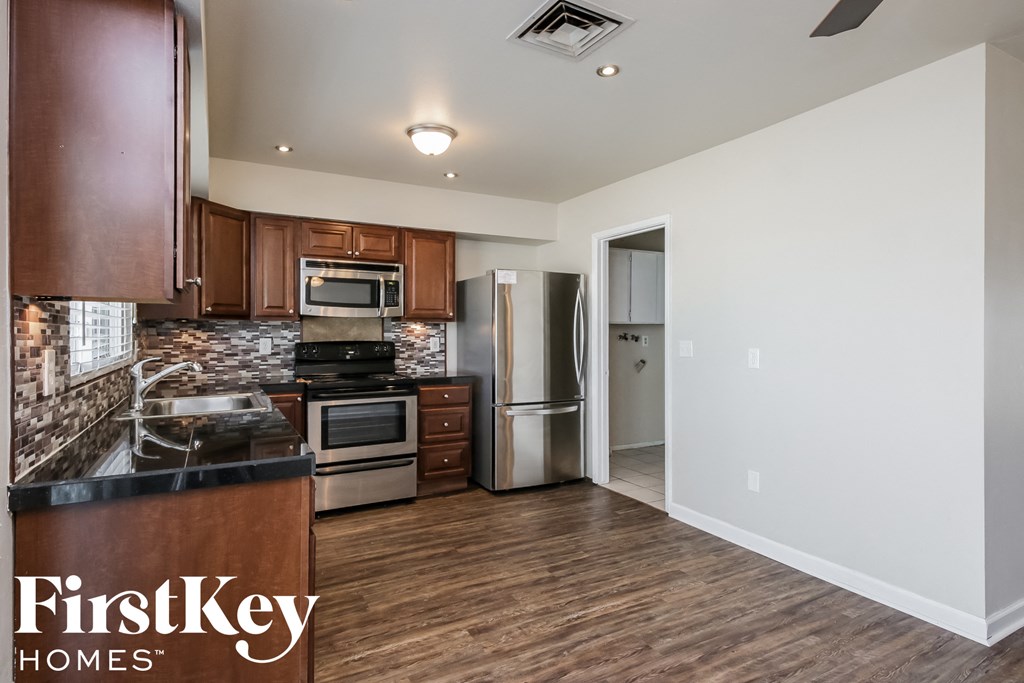 an empty kitchen with wood flooring and stainless steel appliances